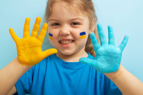 Žlutá a modrá barva na dětských rukou. Koncept symbolů ukrajinské vlajky. - Fotografie, Obrázek