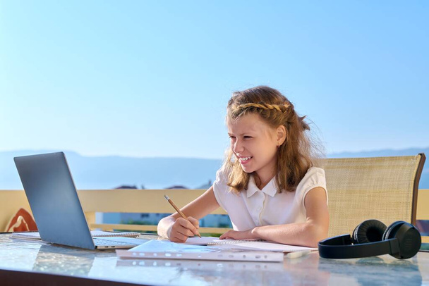 Girl child with headphones is studying using a laptop. - Φωτογραφία, εικόνα