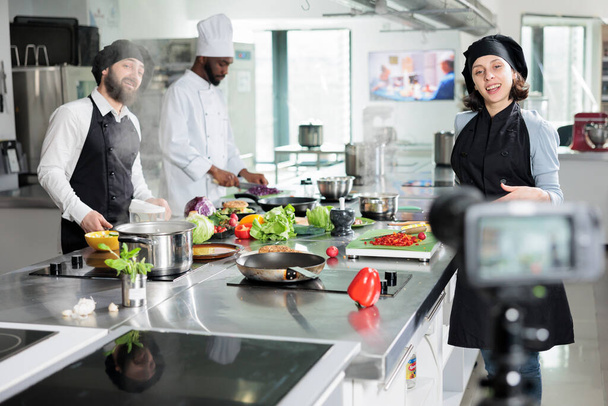 Happy smiling chefs shooting culinary video course in restaurant kitchen while preparing delicious dish. - Photo, Image