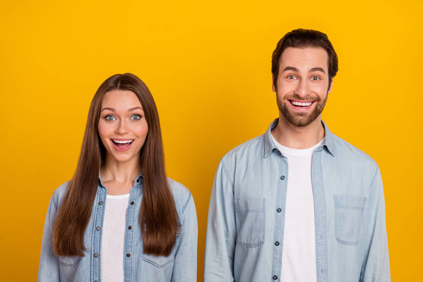 Photo of excited funky sister brother dressed denim shirts open mouth isolated yellow color background - 写真・画像