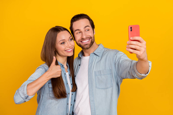 Photo of hooray millennial brown hairdo couple do selfie show thumb up wear jeans shirt isolated on yellow background - Foto, Imagen