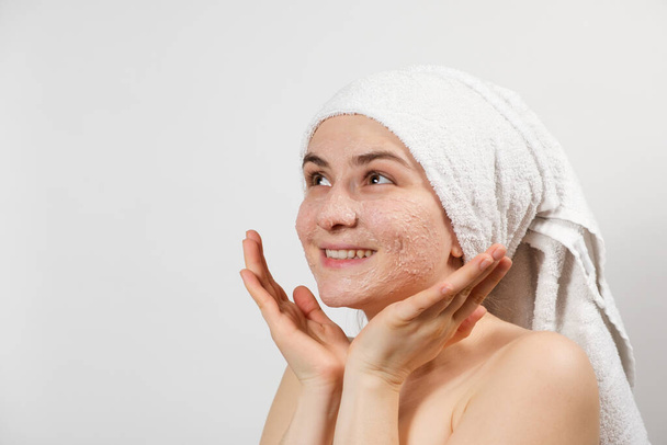 Een mooie jonge vrouw bracht een scrub of masker aan op haar gezicht, gezichtsverzorging, huidreiniging - Foto, afbeelding