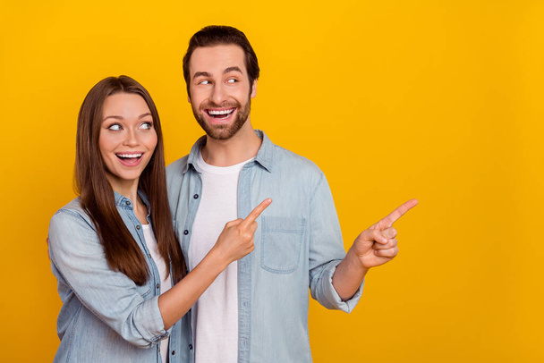 Photo of excited cheerful sister brother dressed denim shirts embracing pointing empty space isolated yellow color background - Foto, Imagem