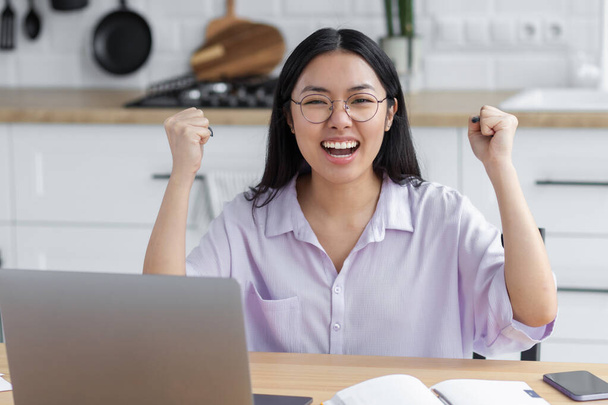 Portrait of excited Asian student woman reading test results celebration success sitting with laptop at home. Happy female freelancer working and having good news, she receive payment - Foto, Imagem