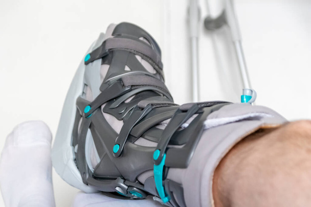 Achilles tendon yırtılması ameliyatından sonra Avrupalı bir adam özel fizyoterapi ayakkabısı ve iyileşmek için koltuk değnekleriyle eve döndü. - Fotoğraf, Görsel