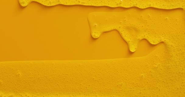 Crème vloeibare gel serum stroomt naar beneden op gele textuur, make-up en cosmetica achtergrond, huidverzorging of haarproduct - Video