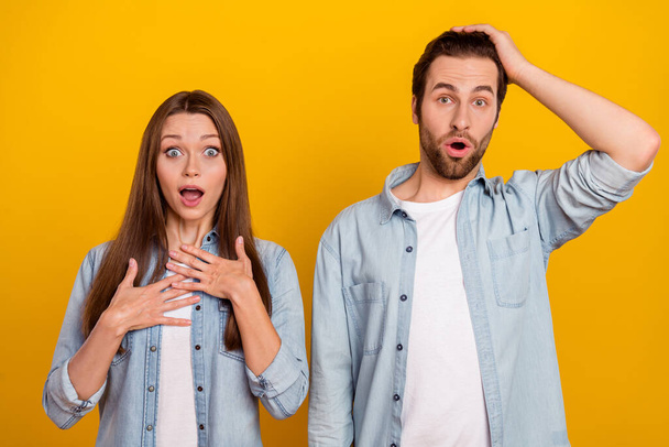 Photo of impressed shocked husband wife wear jeans shirts hands arms head chest isolated yellow color background - Фото, зображення