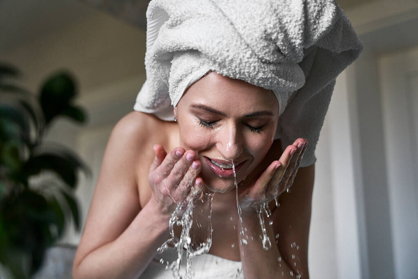 Πρόσοψη της γυναίκας πλύσιμο προσώπου με νερό στο μπάνιο - Φωτογραφία, εικόνα
