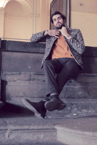 belo e elegante menino de cabelos escuros italiano com jaqueta no centro de Parma nos degraus da Pilotta. Foto de alta qualidade - Foto, Imagem
