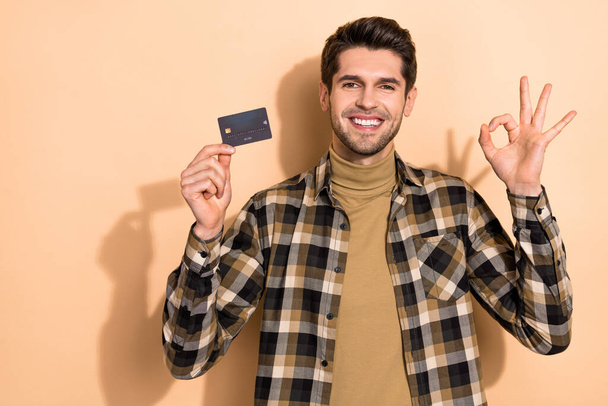 Photo of positive banker demonstrate debit card make okay sign advise savings offer isolated pastel color background - Foto, Imagen