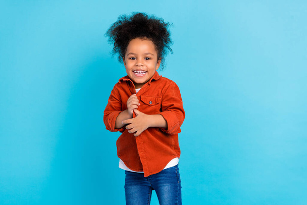 Photo of sweet curly little girl wear shirt jeans isolated on blue color background - Foto, immagini