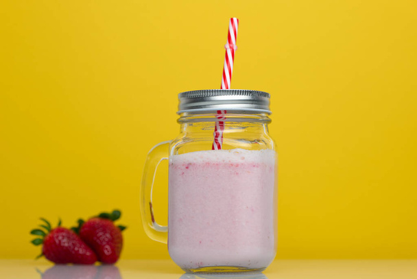 Strawberry smoothie on yellow background with strawberries - Фото, зображення