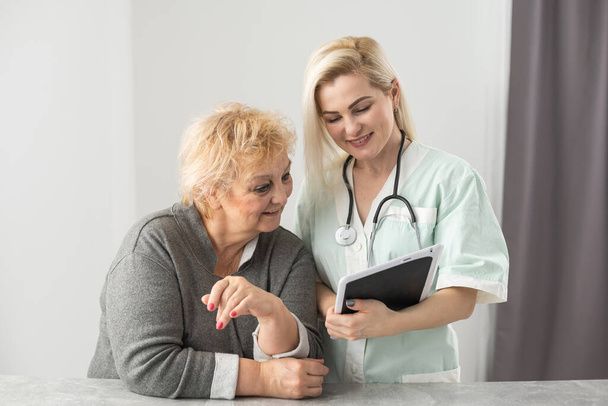 Ev ziyareti sırasında sağlık ziyaretçisi ve yaşlı bir kadın. - Fotoğraf, Görsel