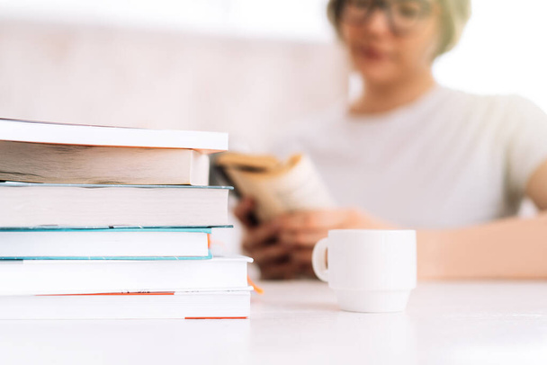 Mädchen mit Brille liest Buch am Tisch mit Tasse Kaffee - Foto, Bild