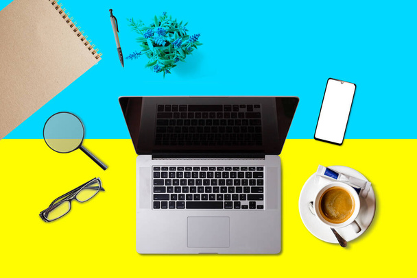 Visit Ukraine concept for your web banner or print materials. Top view of a laptop, coffee cup on Ukraine national flag. Flat style travel planninng website header. - Photo, Image