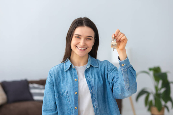 Young handsome young caucasian woman holding keys of new home and friendly smiling happy looking at the camera - Photo, Image