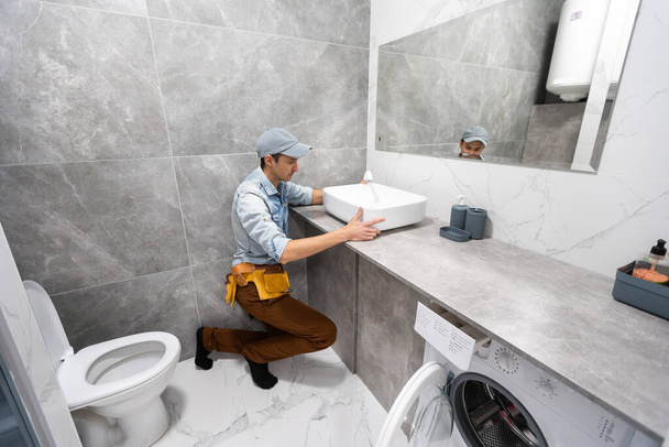 Bir adam banyoda kabine üzerinde lavabo ayarlama - Fotoğraf, Görsel