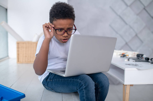 A cute teen sitting at the laptop and looking involved - Photo, image