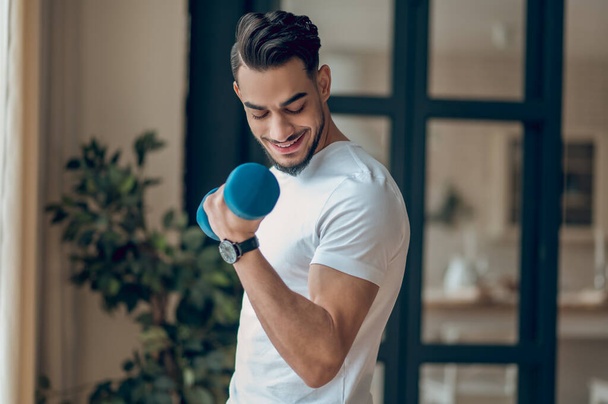 Handsome young man having a workout with dumbbells - Foto, Imagem