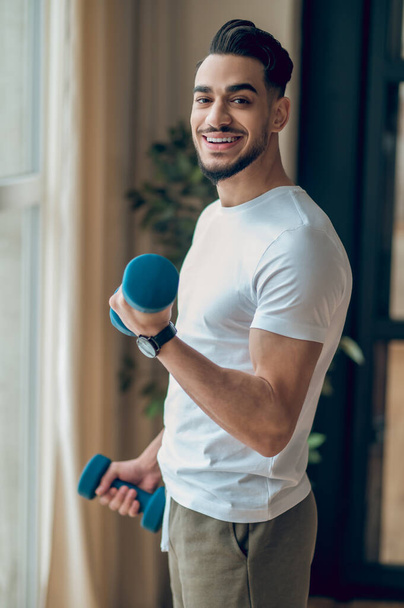 Handsome young man having a workout with dumbbells - Fotó, kép