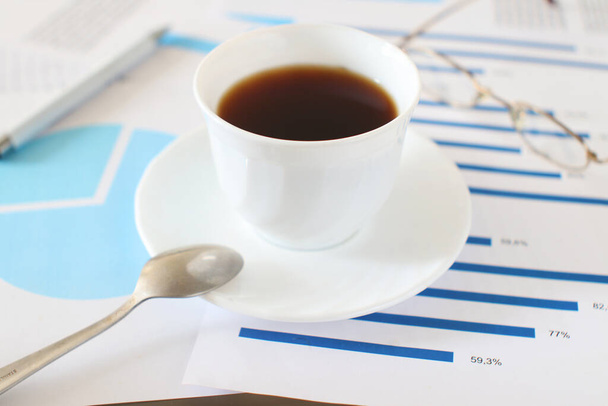 Ένα φλιτζάνι καφέ σε έγγραφα της επιχείρησης. Εργασίες γραφείου και φωτογραφία έννοιας διαλείμματος - Φωτογραφία, εικόνα