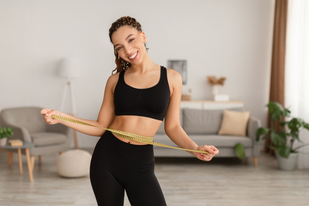 Zwarte dame meten taille met tape na gewichtsverlies Indoor - Foto, afbeelding