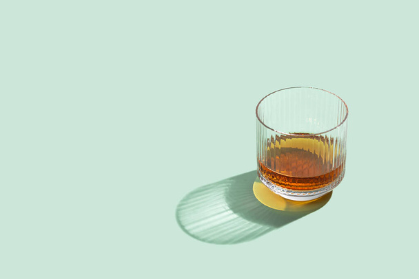 Whisky of Scotch glas op een heldere muntachtergrond. Bovenaanzicht van whiskey of scotch alcohol drinken in kristallen tumblers. Zonlicht zomerindeling met kopieerruimte. - Foto, afbeelding