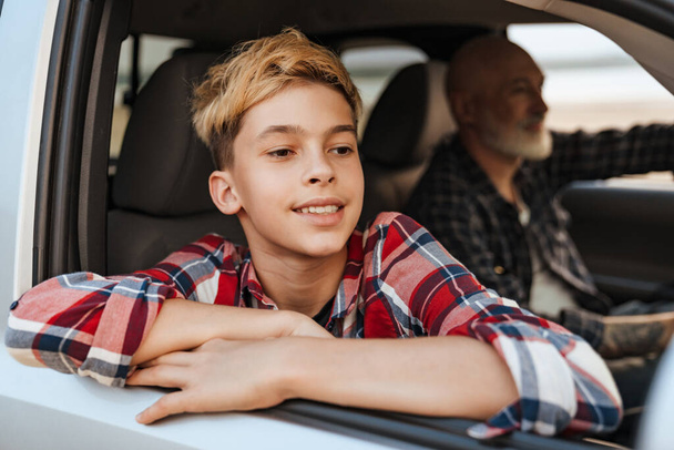 Happy middle aged father and his preschooler son sitting in a car driving, close up of a smiling boy - Foto, afbeelding