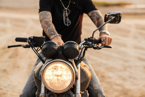 Senior man with tattoo posing on motorcycle outdoors on summer day - 写真・画像