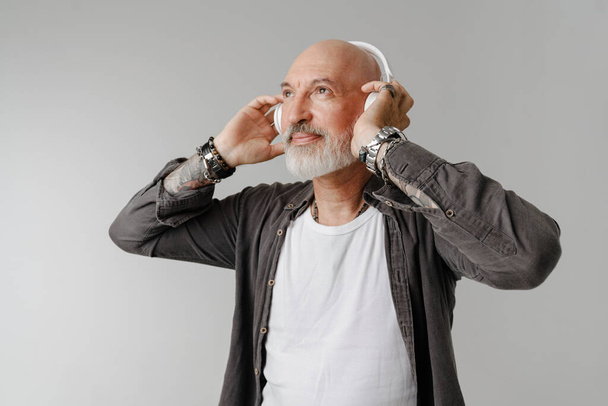 Bald bearded european man listening music with headphones isolated over white background - Fotoğraf, Görsel
