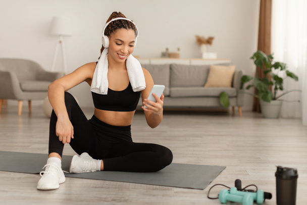 African American Fitness Woman Using Smartphone Exercising Wearing Headphones Indoor - Foto, Imagem
