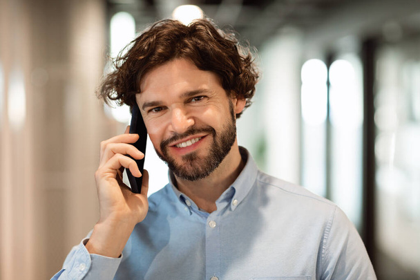 Smiling business man working and talking on phone at office - Foto, Imagem