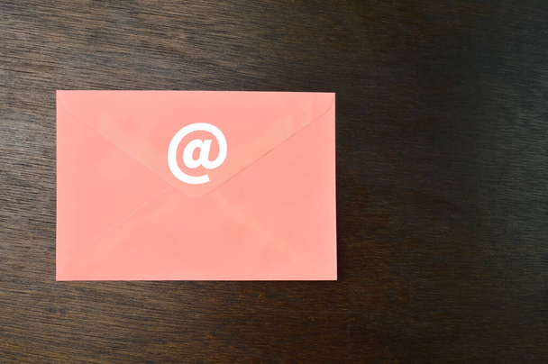 Perzik envelop met e-mail symbool op houten achtergrond - Foto, afbeelding