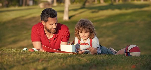 padre e hijo relajarse en la hierba en el parque aprendiendo a dibujar, paternidad - Foto, imagen