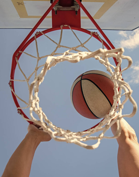 ball goes through basket. man throw the ball in hoop. hands and basketball. - Photo, Image