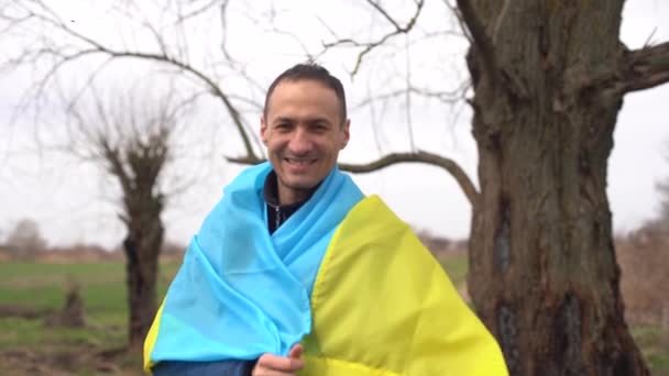 vencedor bem sucedido silhueta homem acenando bandeira ucraniana perto de uma árvore queimada - Filmagem, Vídeo