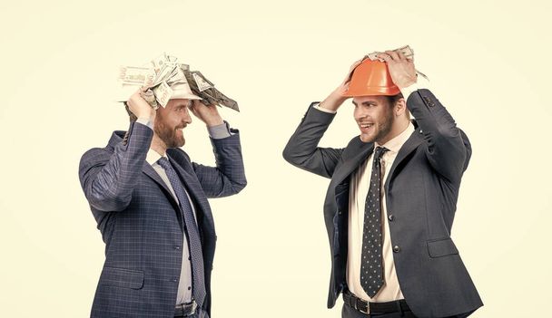 soutien financier. investissement dans un projet architectural. deux hommes d'affaires en hardhat avec de l'argent. - Photo, image