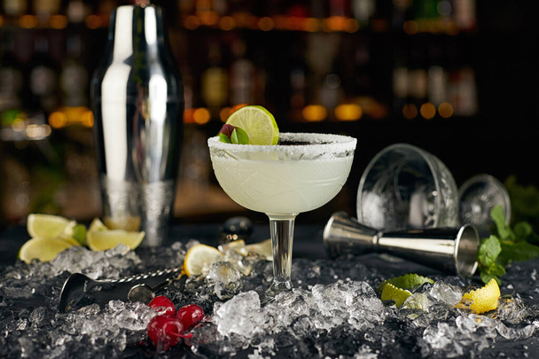 Cocktail Margarita, against the background of bottles, with bar attributes - Photo, Image