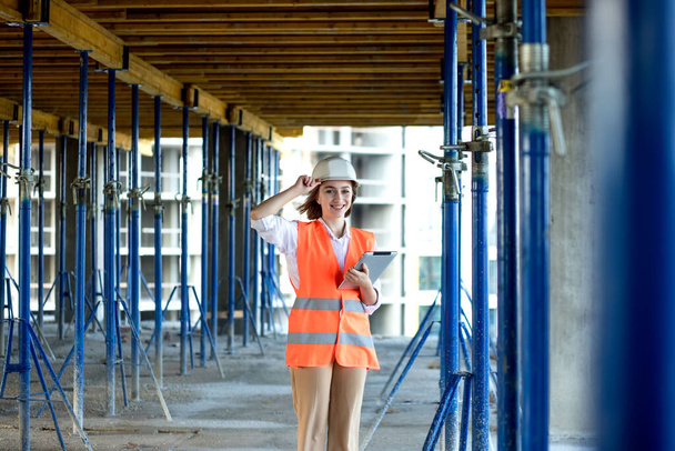 Portrait of beautiful female architect who stands idly and smiles against the background of buildings, outdoors. - Foto, imagen