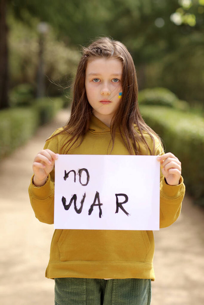 戦争の紛争に抗議ウクライナの貧しい幼児の女の子の子供ホームレスを動揺碑文マッサージテキストとバナーを発生させます戦争屋外ではありません。危機、平和、侵略の停止、ロシア戦争に対する子供。高品質4k映像 - 写真・画像