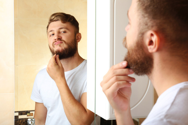 Young man shaving his beard in bathroom - Photo, Image
