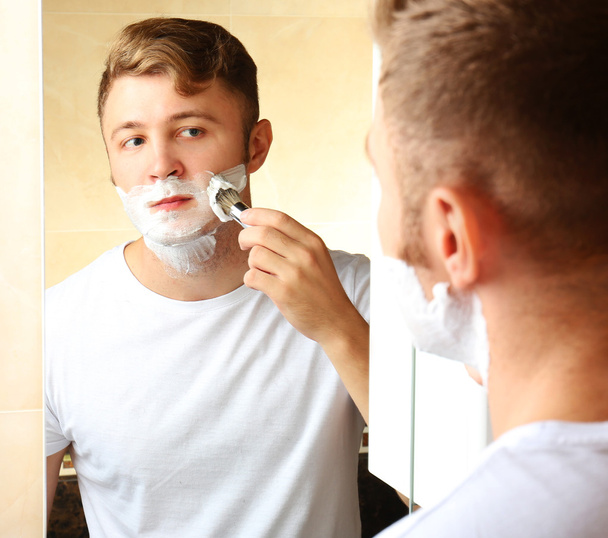 Young man shaving his beard in bathroom - Φωτογραφία, εικόνα