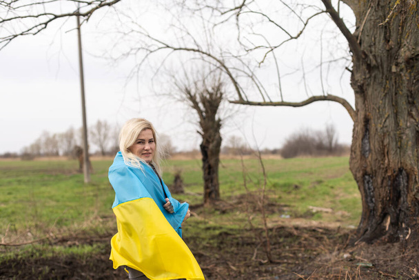 žena vlajka Ukrajiny v blízkosti spáleného stromu - Fotografie, Obrázek