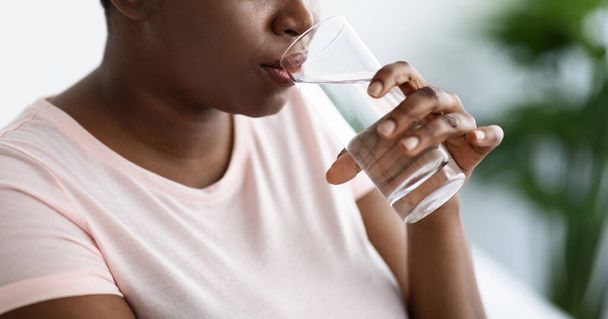 Widok upraw z nadwagą czarny kobieta picia wody mineralnej ze szkła w pomieszczeniach, panorama - Zdjęcie, obraz