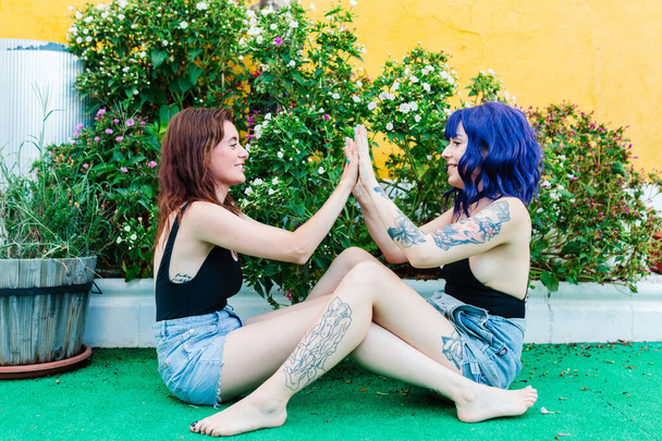 Happy young women playing patty cake in backyard - Фото, изображение