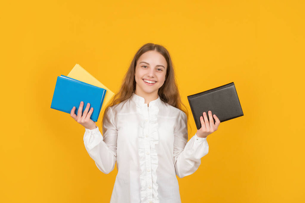 smiling teen girl hold school workbook on yellow background, study - Foto, imagen