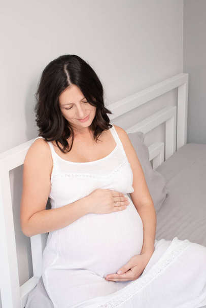 очікує мати з величезним животом. солодкий час вагітності. щаслива жінка з вагітною животом у світлій спальні. домашній затишний інтер'єр
 - Фото, зображення