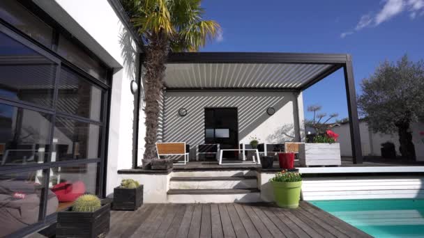 Trendy patio esterno pergola struttura ombreggiante, tenda e tetto patio, sala giardino, sedie, griglia in metallo circondato da paesaggio - Filmati, video