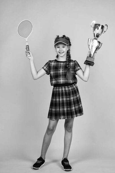 teen kid in fitness cap holding tennis or badminton racket and championship cup, sport champion - Photo, Image
