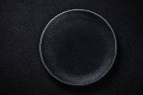 Black plate at black background. Top view. - Foto, Imagem